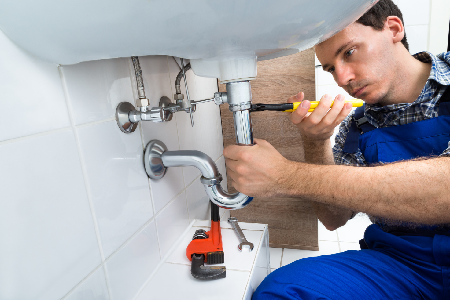 Plumber fixing sink pipes in a bathroom